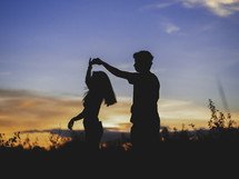 silhouette of a couple dancing holding hands at sunset 