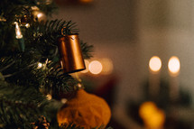 Brown ornament and bell on a Christmas tree with twinkle lights