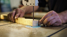 Hands of carpenter sharpens wooden part on grinding machine. Handwork concept, woodworking workshop. High quality photo