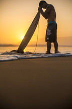 man with his head bowed in prayer over his surfboard