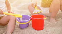 Unrecognizable babies playing on beach in sand with plastic toys. Summer sunny day. Children, family, toddler boy concept. High quality photo