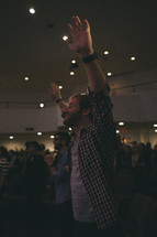 A man with hands raised in worship to God at a worship service. 