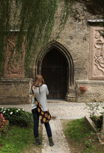 woman taking a picture of an arched wooden door 