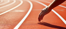Running track with white lines in stadium. Sport background. Close up of human hand on running track.