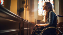 Young woman in a wheelchair praying in a Church. Selective focus.