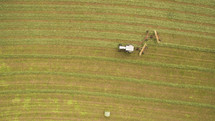 An aerial view of a field being harvested by a combine.