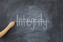 crossing through the word integrity on a chalkboard 