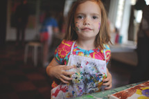 a girl child in a painting smock 