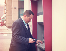 businessman at an ATM in a city 