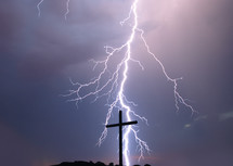 lightning striking behind a cross