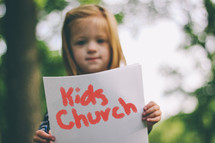 girl holding a Kid's Church sign