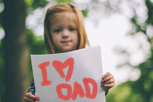 "I love Dad" sign held by a child.
