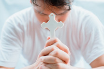 a man with head bowed holding a cross praying 