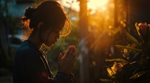 Young Asian woman praying in the morning with sunlight background. Christian concept.