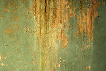 Green paint flaking off clay wall.