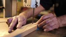 Hands of carpenter sharpens wooden part on grinding machine. Handwork concept, woodworking workshop. High quality photo