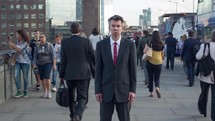 Timelapse of a businessman standing still as pedestrians walk past on London Bridge. London - editorial use only