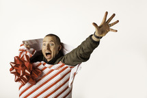 Christmas consumerism - man wrapped up in Christmas paper reaching out for help