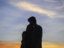 a couple  holding each other at sunset 