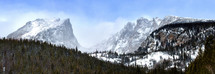 Panorama of Hallet Peak and Flattop as viewed from Rocky Mountain National Park as snow blows over the mountain peaks
