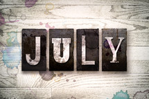 word July on wood background 