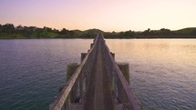 Beautiful evening in wooden bridge over ocean bay in New Zealand nature landscape
