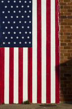 American flag painted om brick wall behind sidewalk.