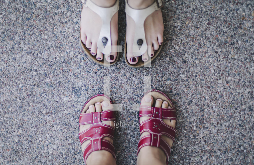 two girls facing each other looking down at feet