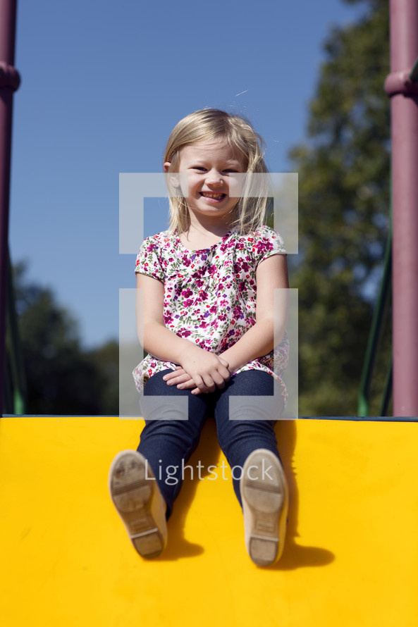 a girl sitting on a slide 