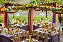 ornately decorated tables at a wedding reception, gold, purple wedding design , floral drapes chairs linens dinner