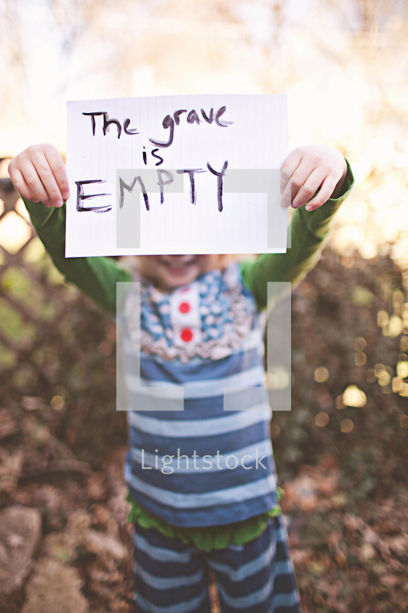 girl holding a sign that says "The grave is empty"