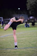 a girl soccer player stretching on the soccer field 