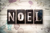 word noel on a white wash wood background 