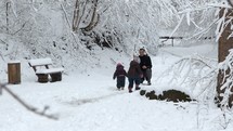 father playing outdoors with his daughters in the snow 