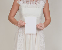 a bride holding a blank piece of white paper 