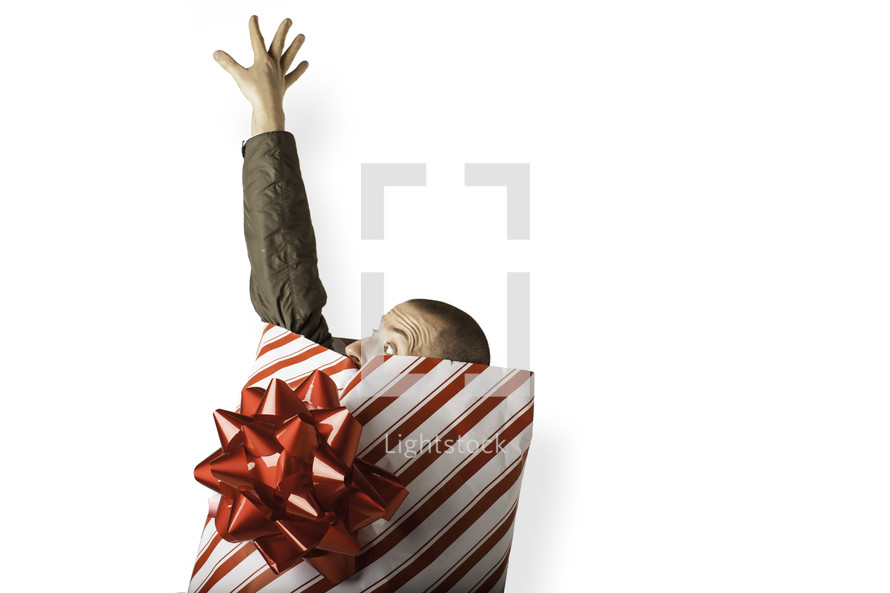 Christmas consumerism - man wrapped in Christmas paper reaching out for help