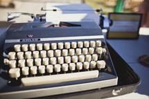 A traveling typewriter with a piece of paper attached 