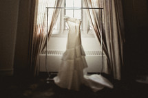 Wedding dress hanging in front of a window