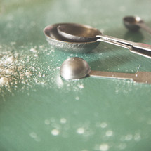 measuring spoons and flour on a countertop 