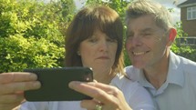 Active senior caucasian couple pulling funny faces taking selfies on a smartphone
