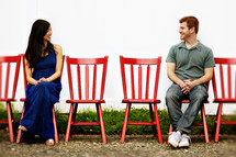 man and woman sitting in red chairs