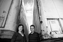 man and a woman standing between two tractor trailers