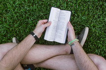 man reading a Bible in the grass 