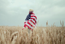 Patriot woman standing with american national flag in rural wheat field landscape. 
