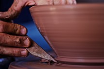 Hands molding a bowl on a potter's wheel