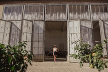 A woman standing in a doorway fig trees in the foreground 