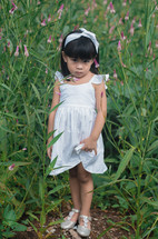 a little girl in a dress standing in a field 