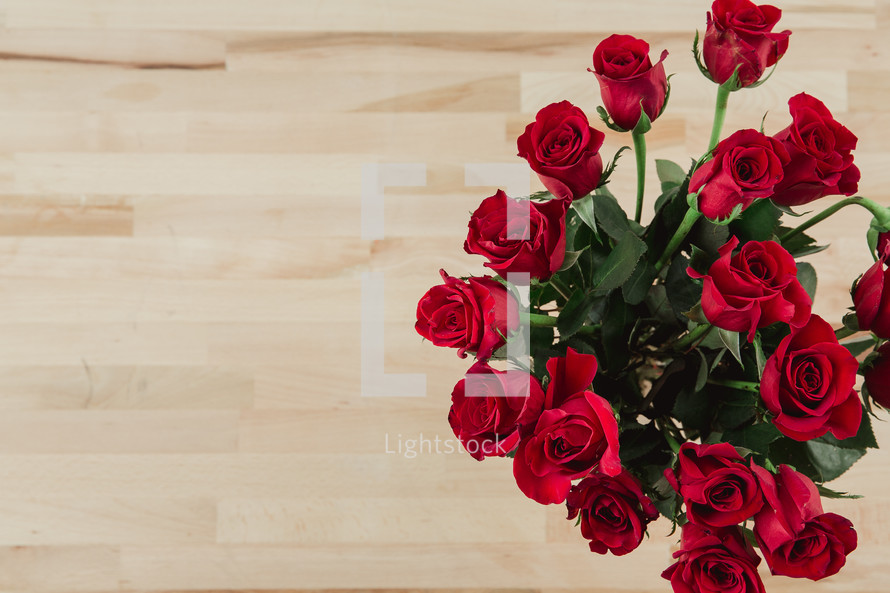 Red roses on a wood grain table.