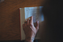 Hand on an open Bible; reading scripture.