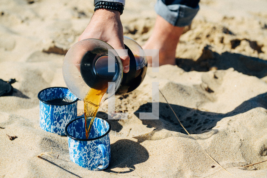 pouring coffee into mugs on a beach 
